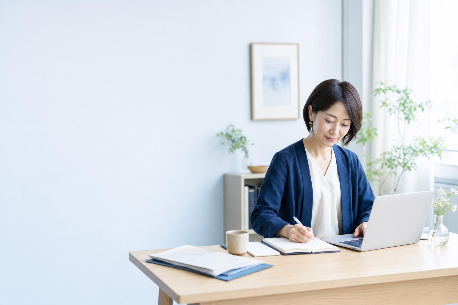自然光の入るホームオフィスでノートパソコンに向かって働く女性